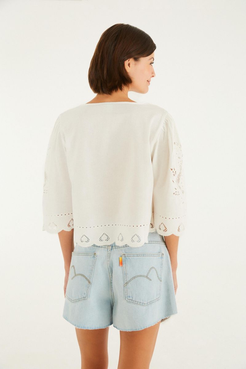 Vista trasera del short jeans evase azul claro con bolsillos decorativos y blusa blanca de encaje.