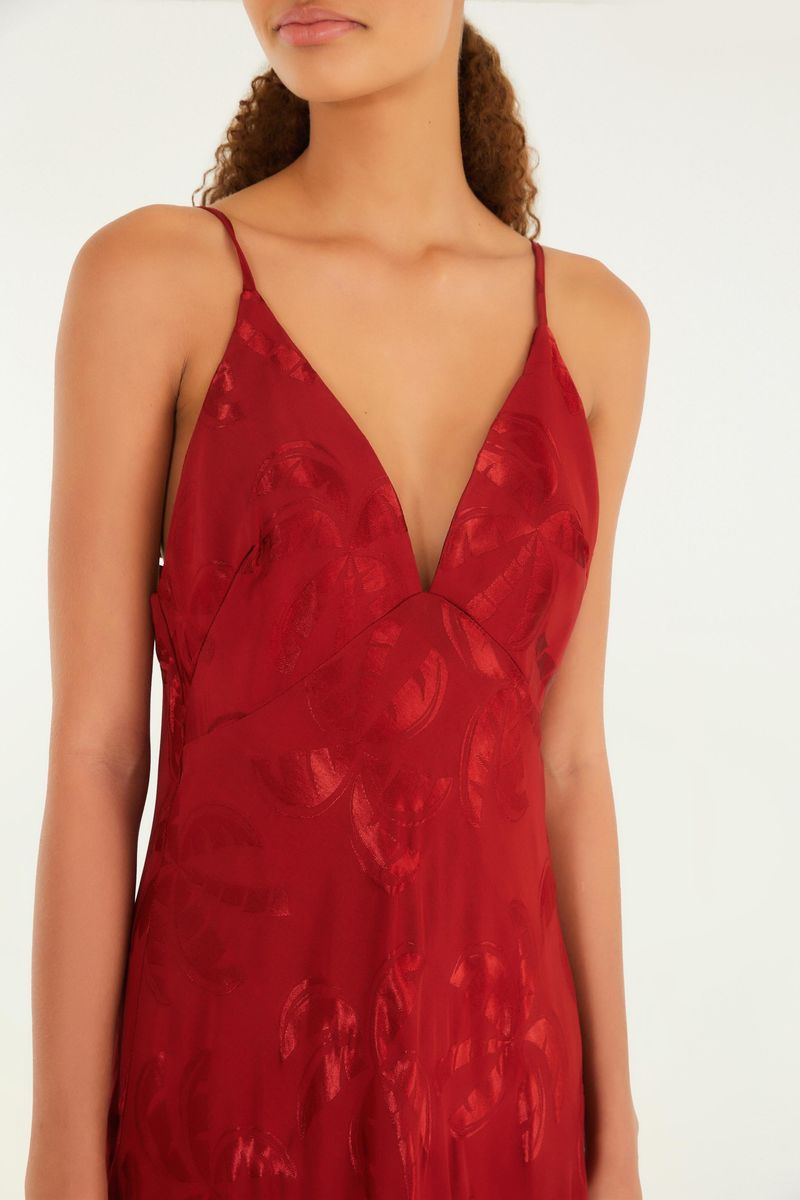 Detalle del escote en V del vestido rojo con estampado jacquard de coqueiros.