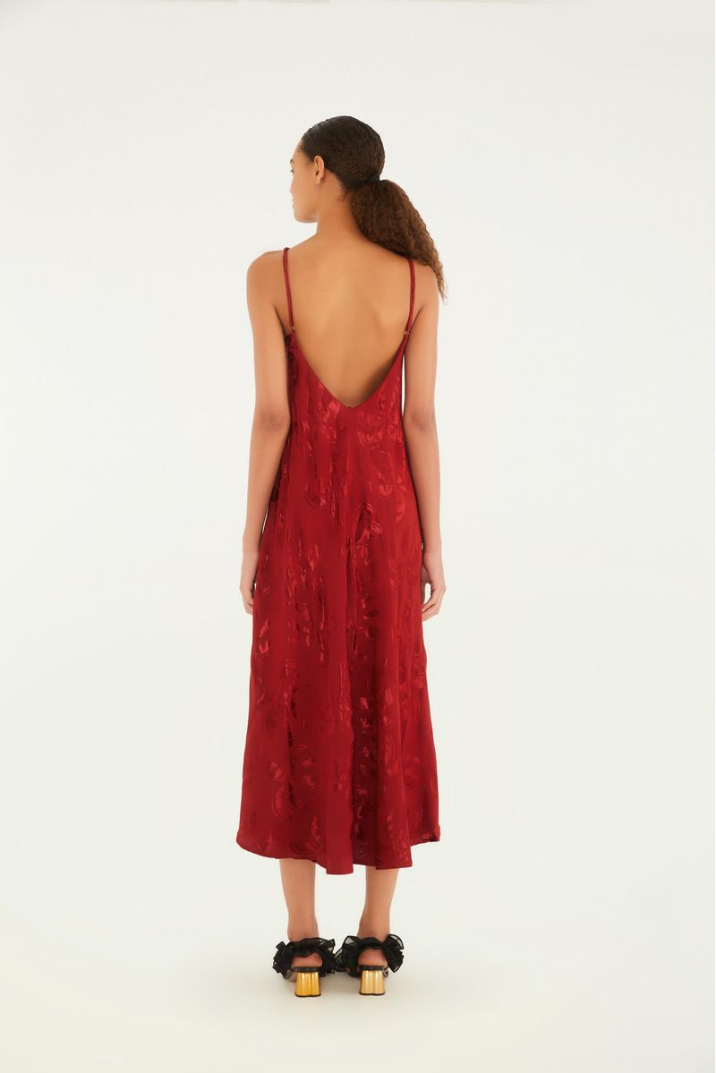 Vista posterior del vestido rojo con estampado jacquard de coqueiros, mostrando los tirantes delgados y el largo midi.