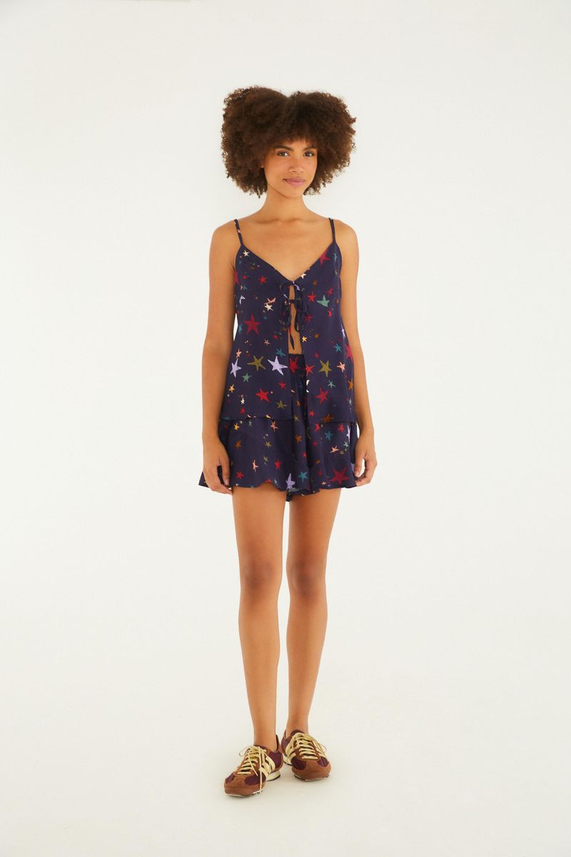 Modelo usando un conjunto con short estampado de estrellas coloridas y fondo azul oscuro.