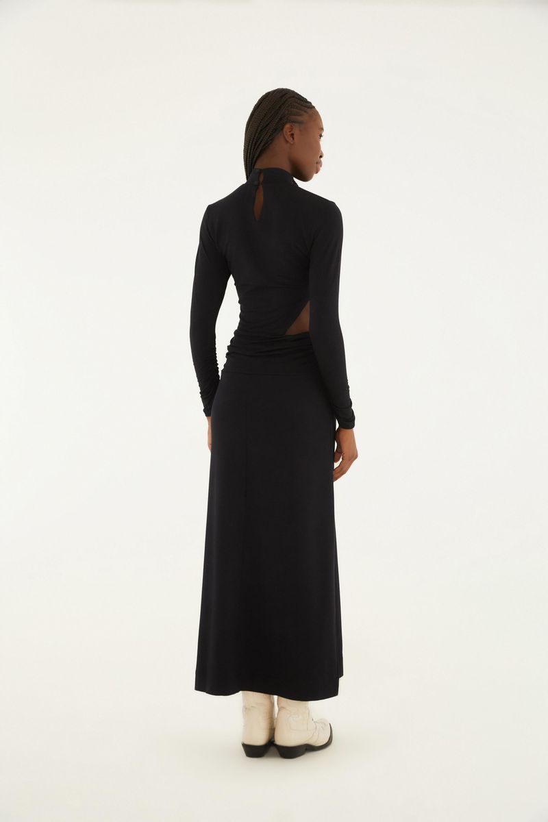 Vista trasera del vestido negro con corte asimétrico y detalle en el cuello alto.