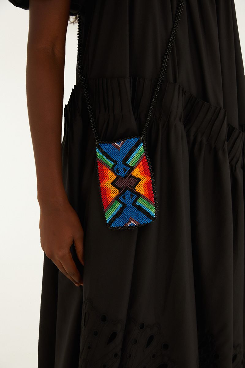 Imagen de una bolsa artesanal con estampado geométrico en abalorios coloridos, siendo usada por una modelo.