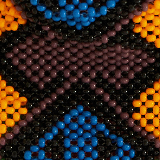 Imagen de una bolsa artesanal con estampado geométrico en abalorios coloridos, vista trasera.