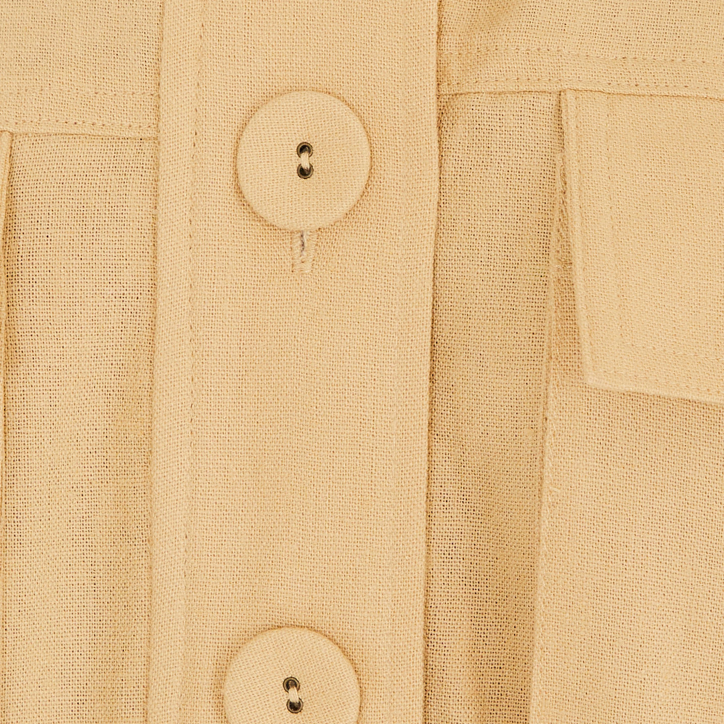 Primer plano del botón y la tela de la chaqueta bomber beige.