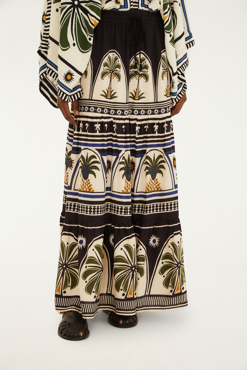 Modelo usando una falda larga con estampado tropical, vista lateral.