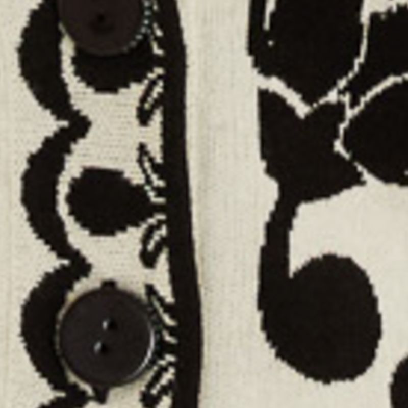 Close-up del estampado floral y arabesco del cardigan largo tejido.
