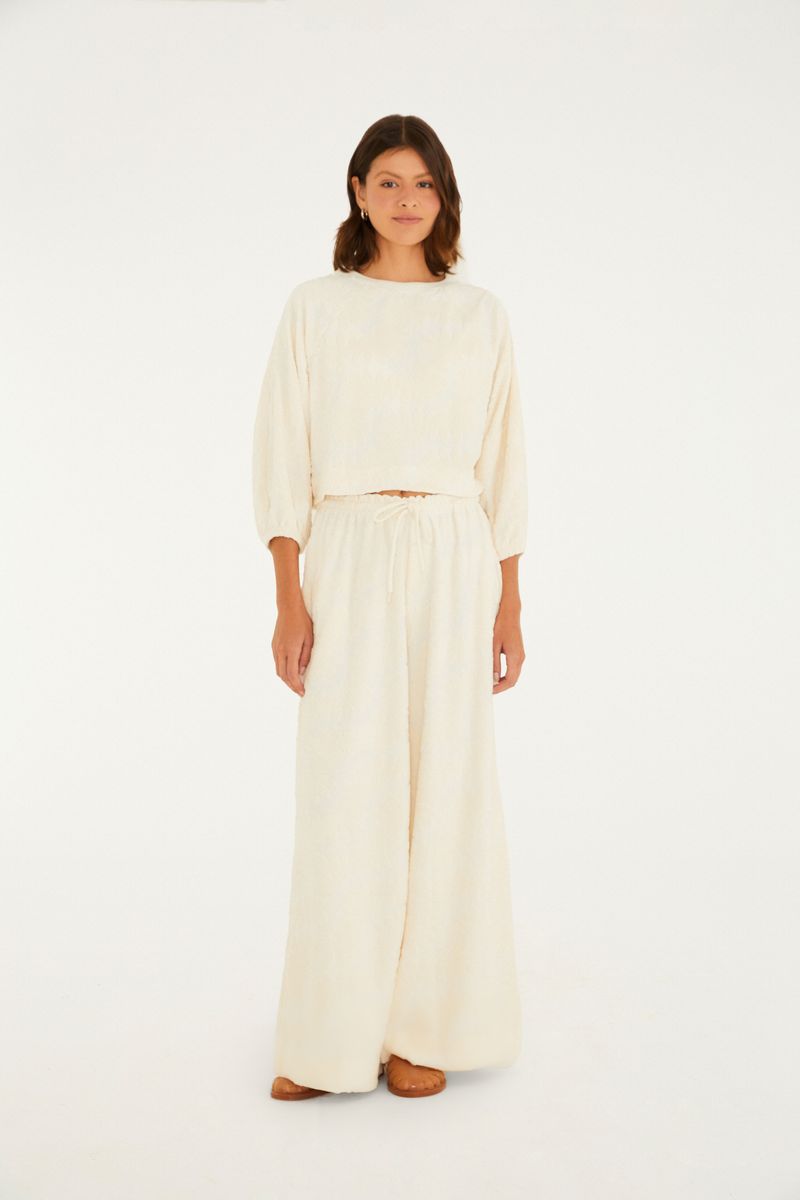 Pantalón acampanado en lurex beige con cintura alta y amarre, vista frontal.
