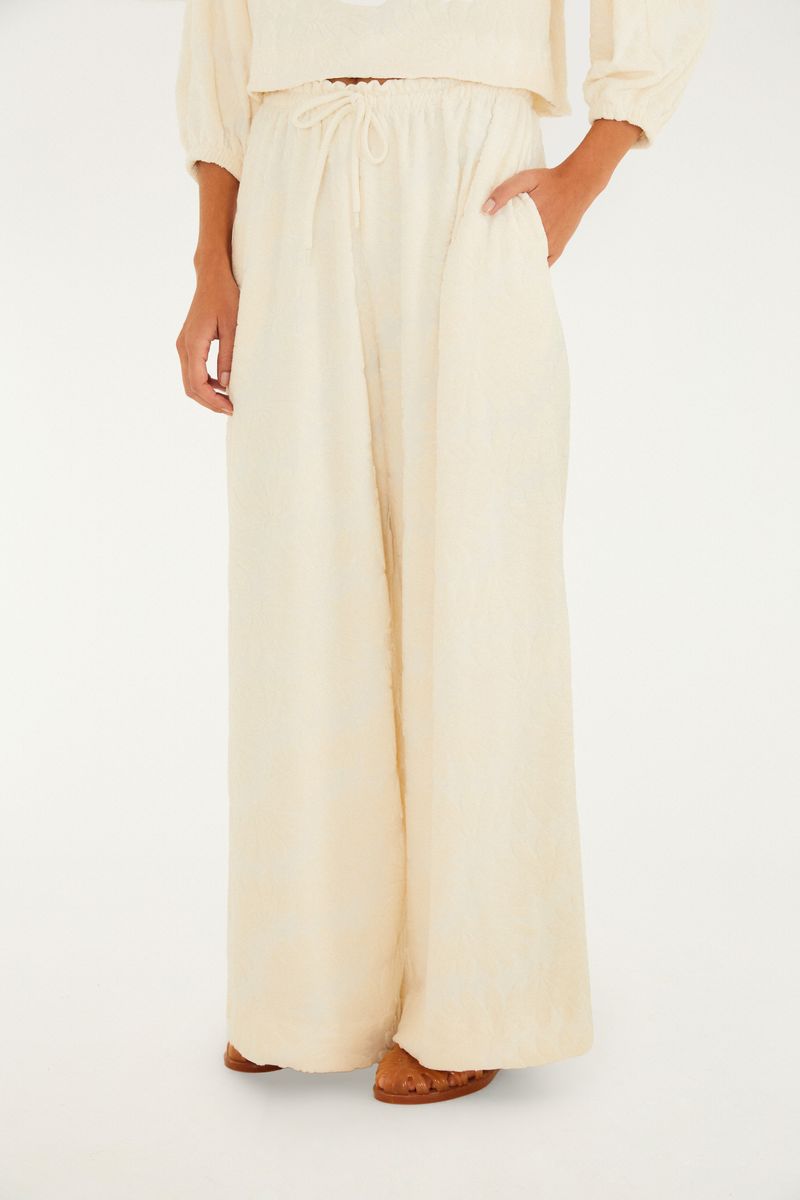Detalle de cintura alta y amarre del pantalón acampanado en lurex beige.