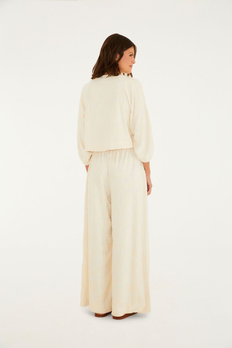 Detalle del tejido lurex beige del pantalón acampanado.