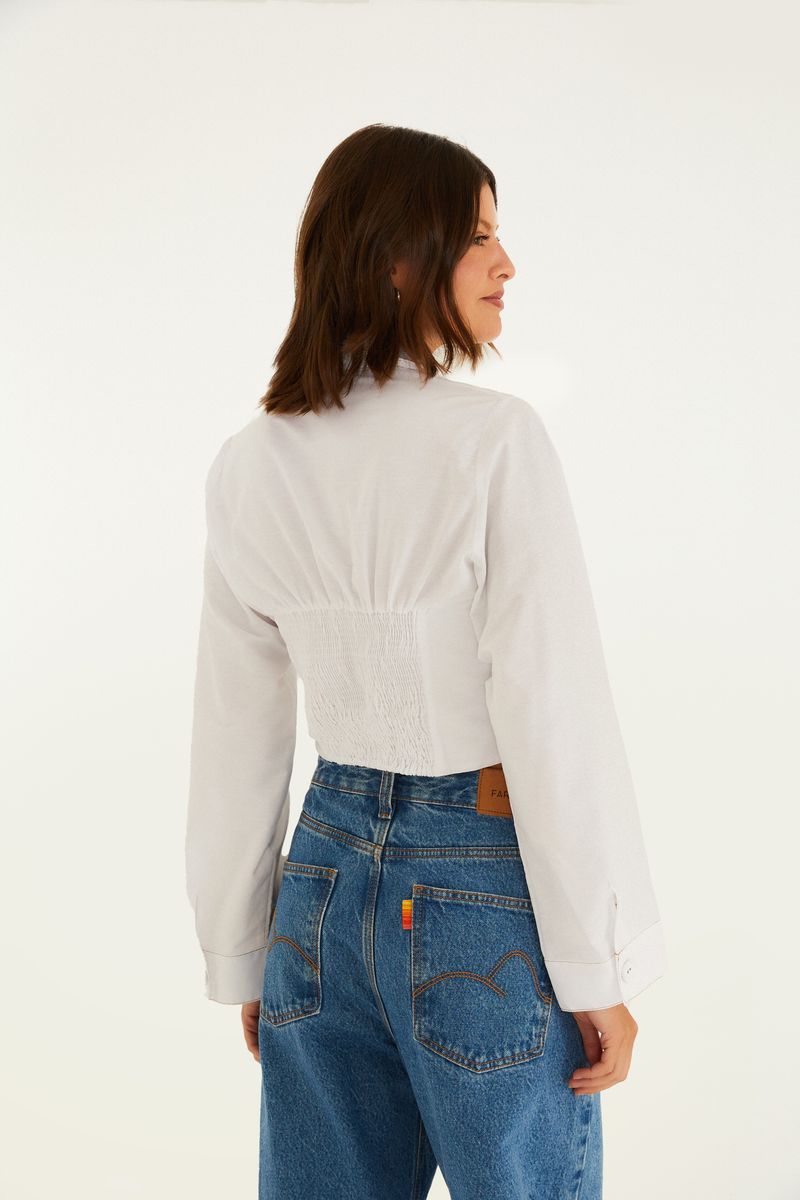 Vista lateral de la camisa blanca con diseño de corsé.
