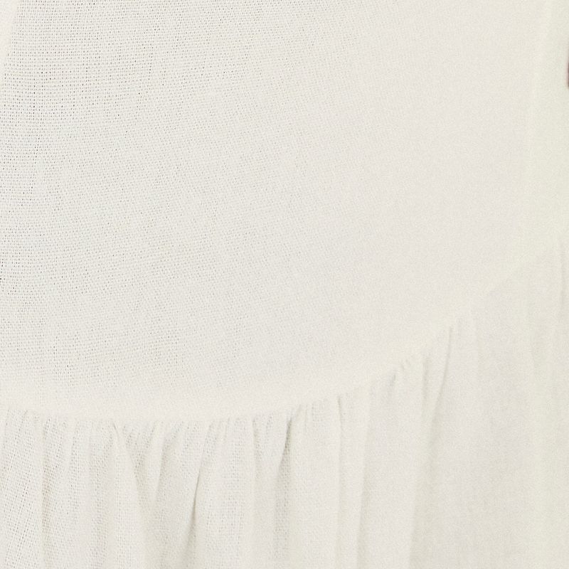 Detalle del acabado del vestido corto blanco crema mostrando el borde de la tela.