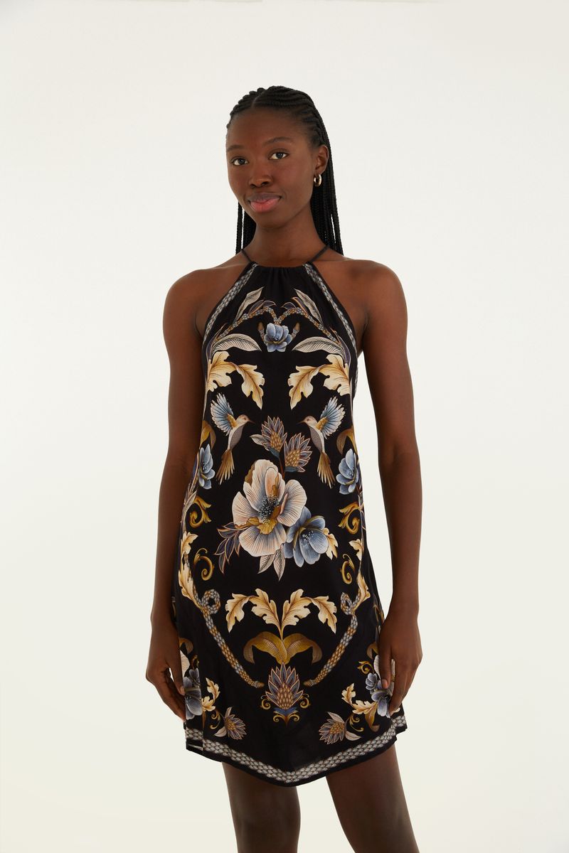 Foto de un vestido corto con tirantes tipo pañuelo, con estampado floral y botánico de tonalidades azul, dorado y beige sobre fondo negro, vista de frente.