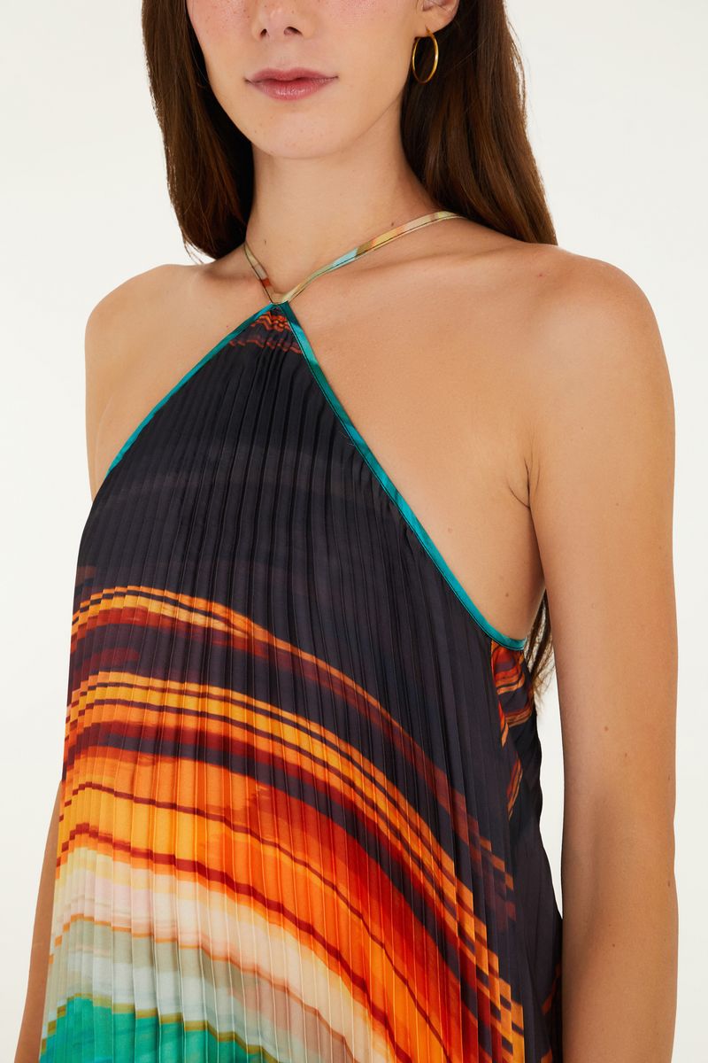 Detalle del escote frente única del vestido plisado con estampado vibrante.