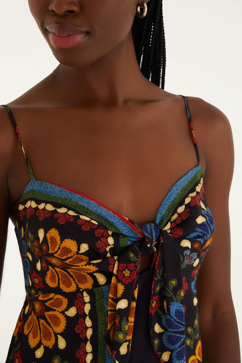 Detalle del escote del vestido corto con estampado floral y lazo frontal.