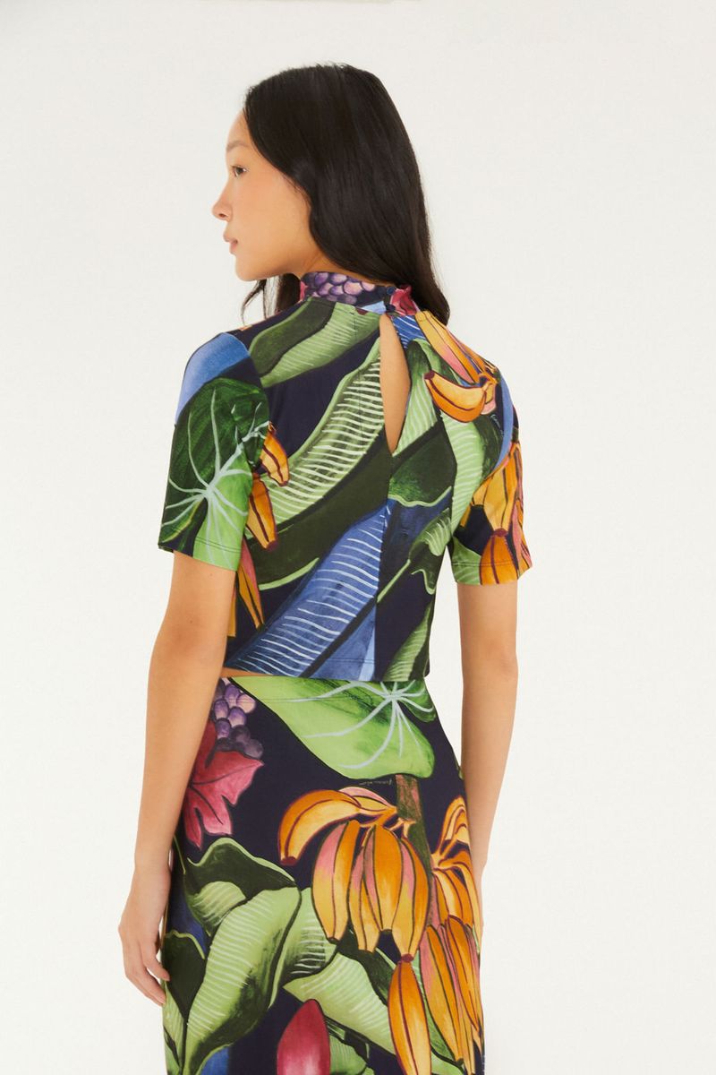 Vista trasera de la blusa cropped con estampado tropical y detalle de cierre.