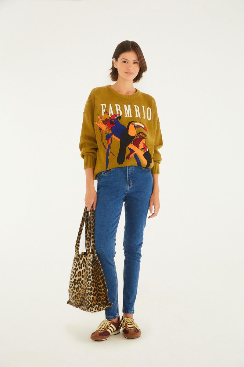 Modelo usando pantalones vaqueros ajustados azules con blusa estampada y tenis.