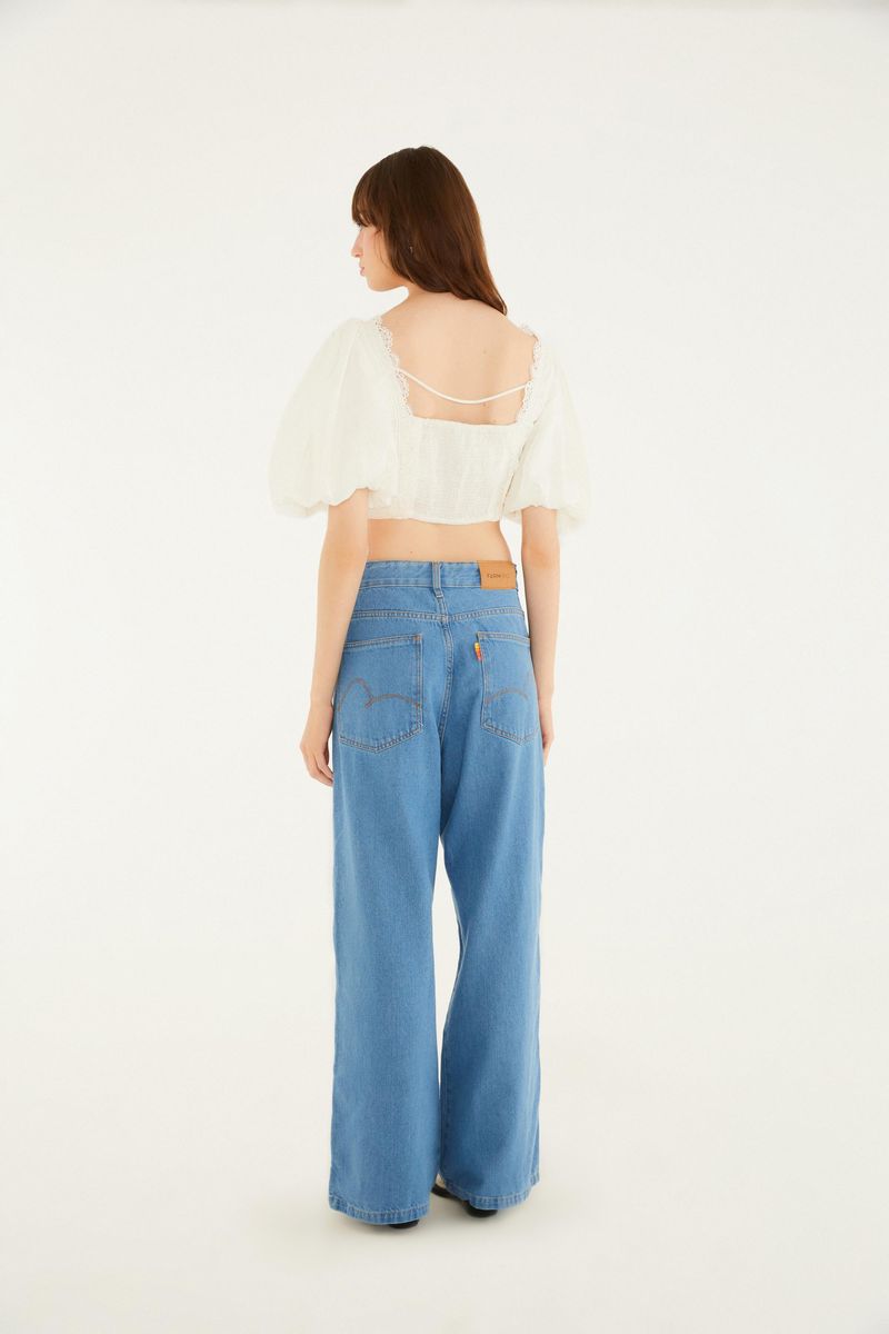 Vista trasera del pantalón jean azul claro con bolsillos y cintura alta, combinado con una blusa blanca.