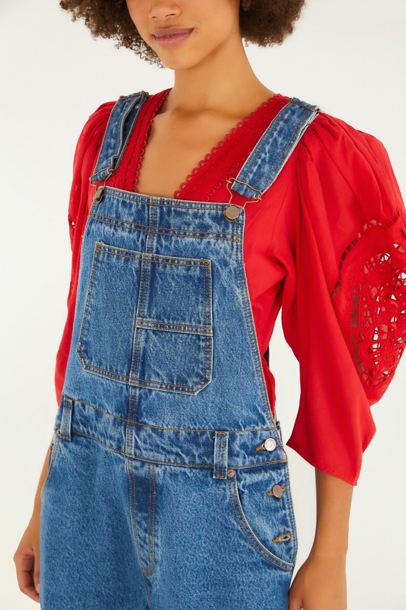 Detalle de la parte superior de la salopette de mezclilla media con blusa roja con encaje.