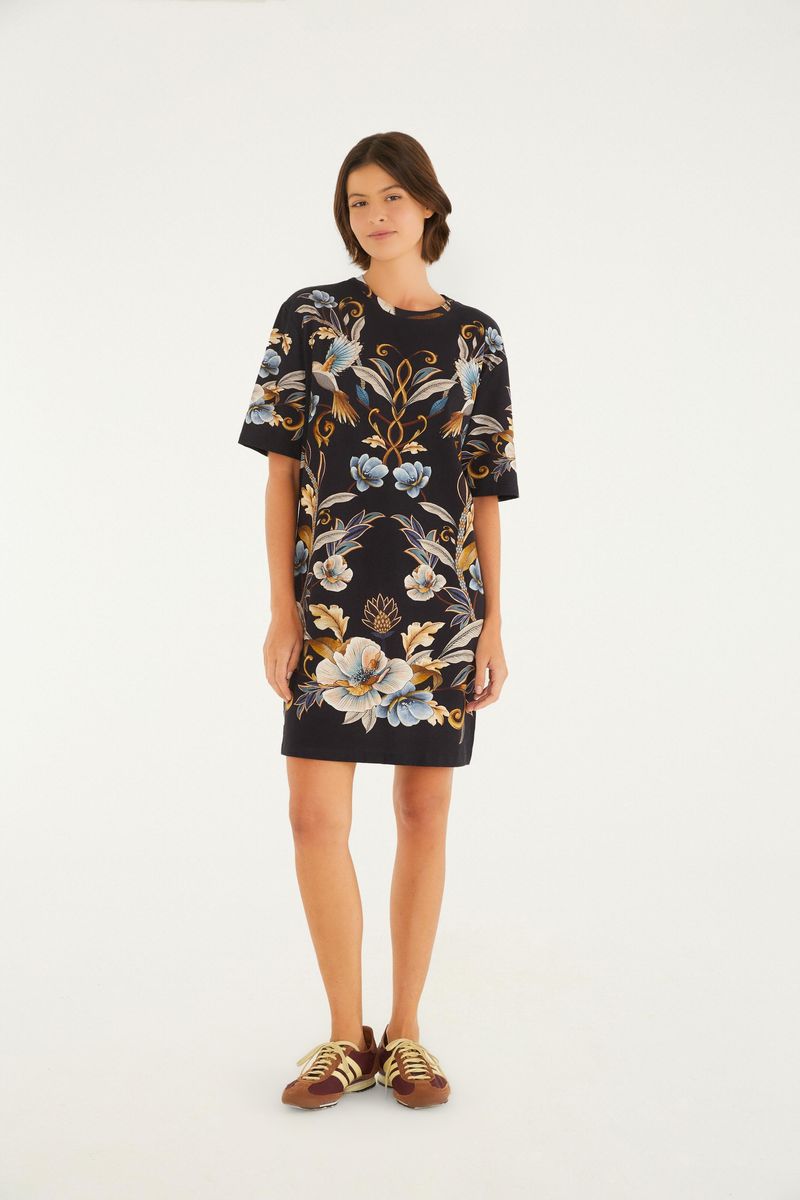Vestido tipo camiseta con estampado floral y botánico en fondo negro, exhibido en modelo de cuerpo completo.