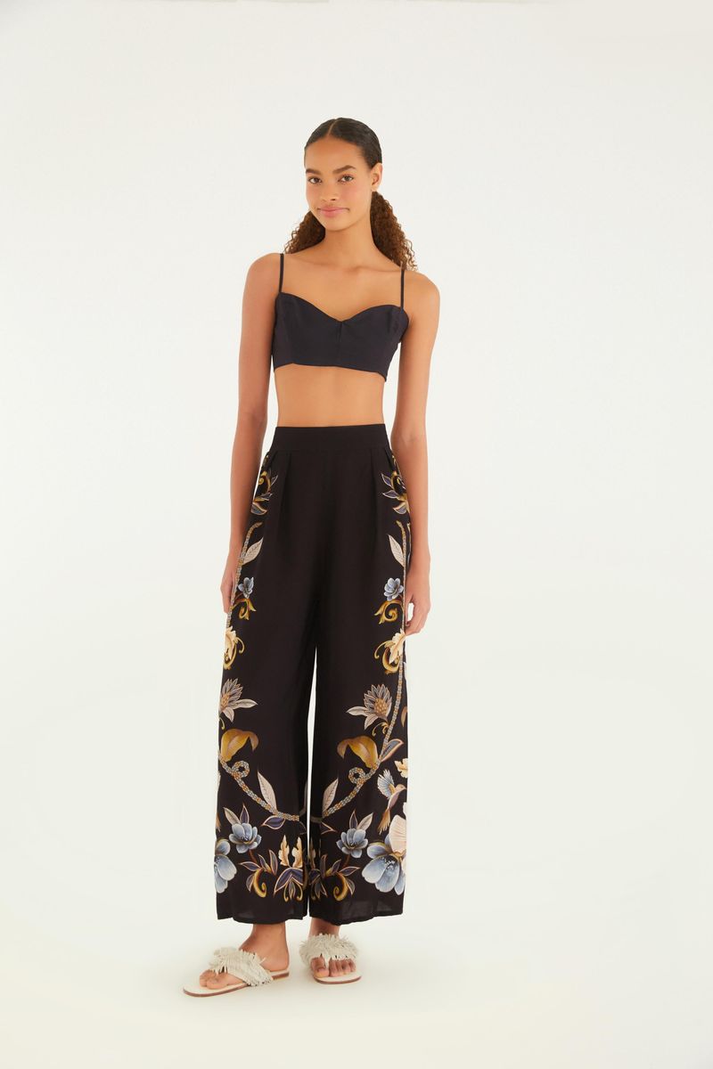 Conjunto con top negro y pantalón estampado floral visto de cuerpo entero.