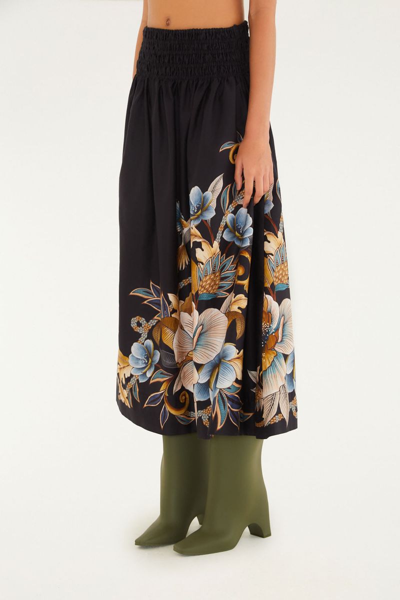 Falda corta con estampado floral en fondo negro, destacando detalles en azul y dorado.