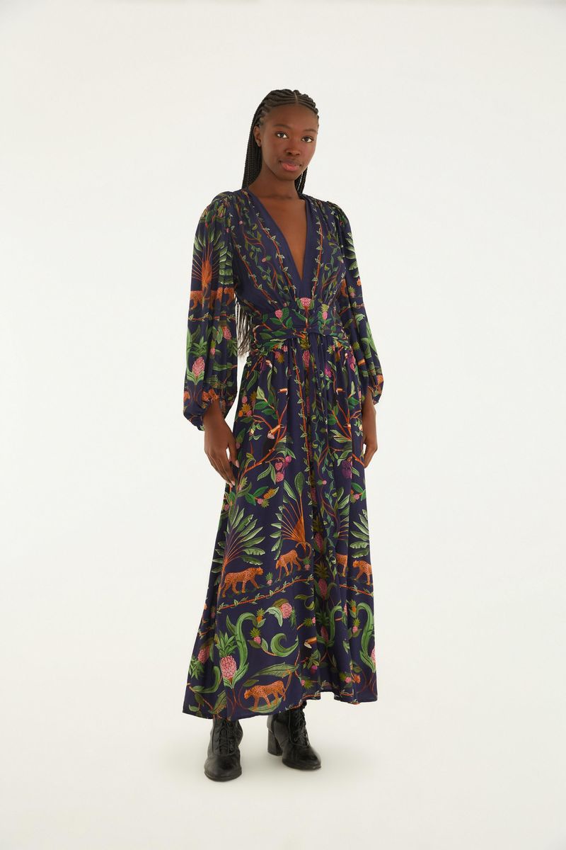 Modelo luciendo un vestido largo estampado con temática de bosque dulce, con mangas largas y escote en V.