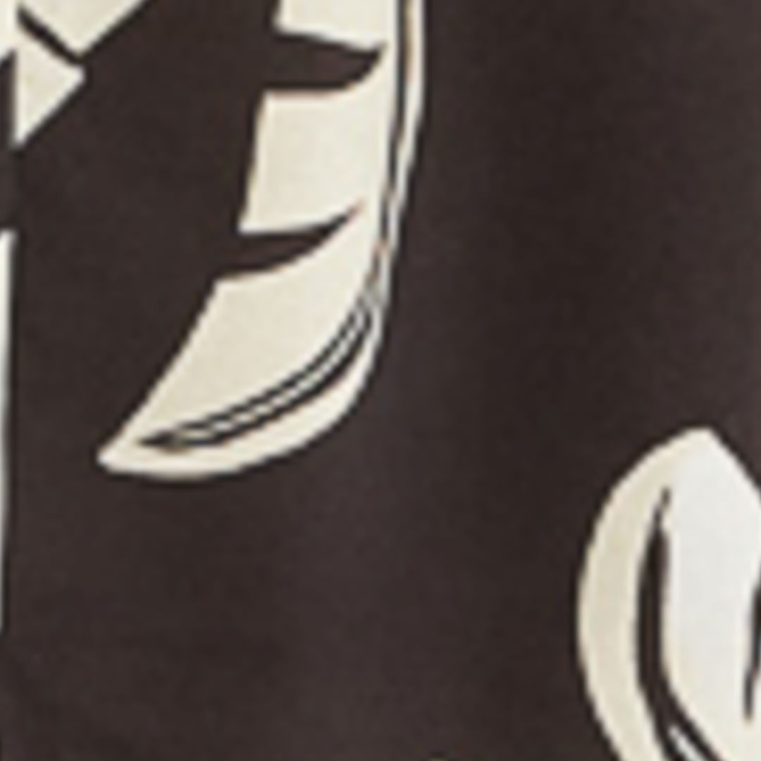 Imagen mostrando un detalle de la tela del vestido con diseño de hojas de palmera estilizadas sobre fondo oscuro.