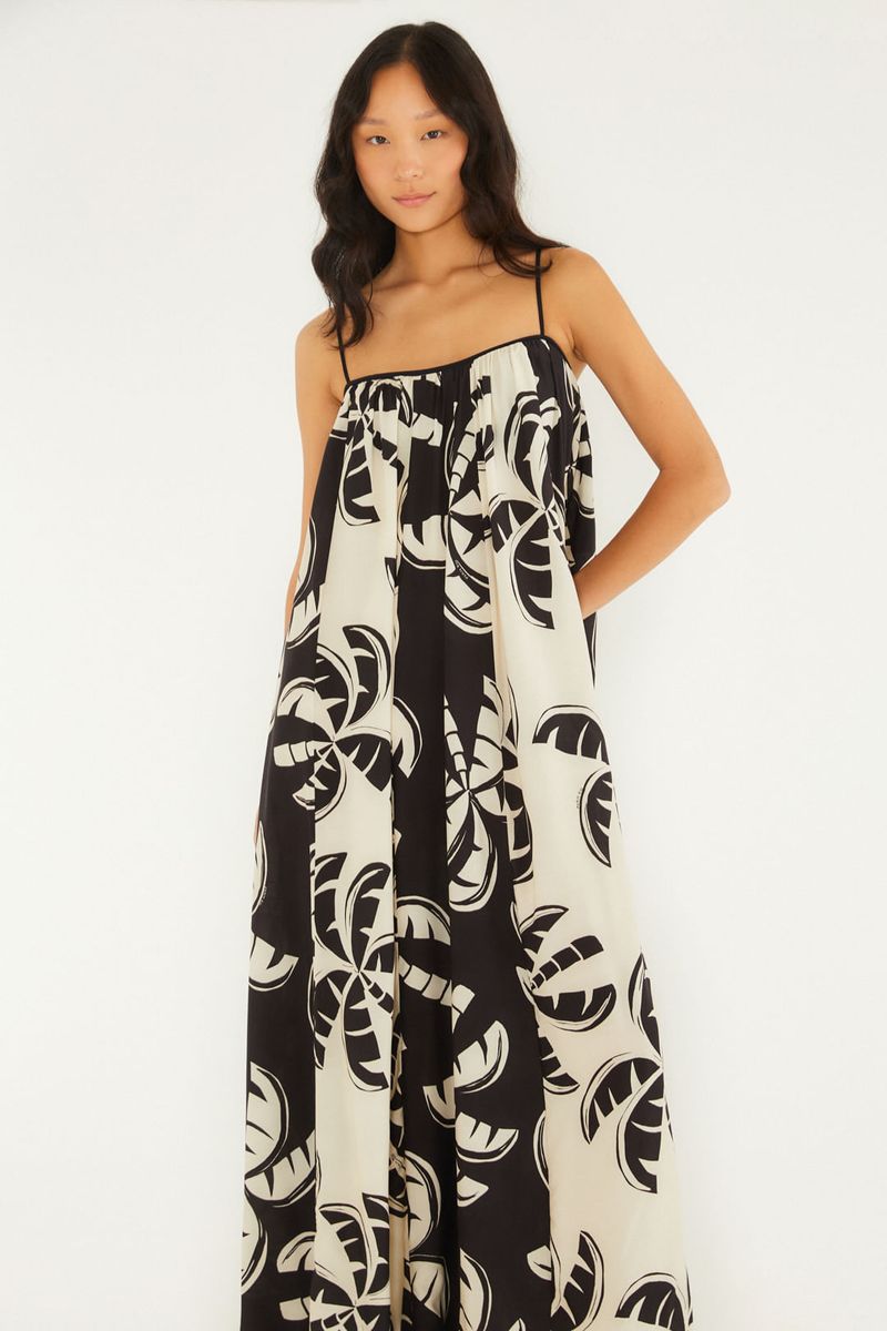 Imagen de una modelo usando un vestido largo estampado con tirantes finos, vista lateral.