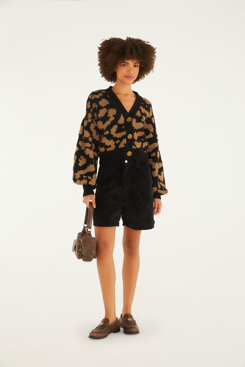 Modelo luciendo un cardigan corto tejido con estampado de leopardo, combinado con shorts y mocasines.