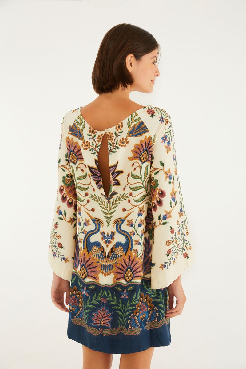 Vista trasera del vestido corto con estampado floral y botánico, destacando el escote en V en la espalda.