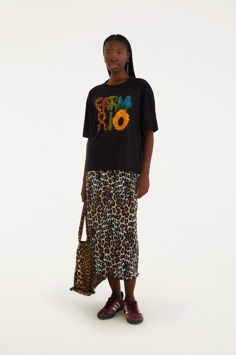 Modelo usando falda plisada midi con estampado de leopardo y camiseta negra con estampado colorido.