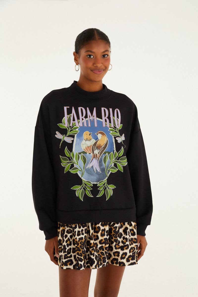 Imagen de una modelo vistiendo un vestido de sudadera negro con estampado de pájaros y hojas en la parte frontal, combinado con una falda de estampado animal.