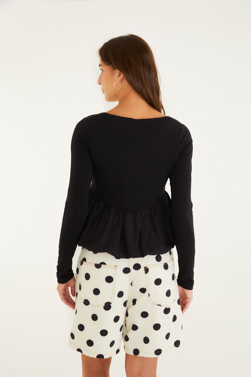 Camisa negra con mangas largas y diseño peplum vista desde la parte trasera.