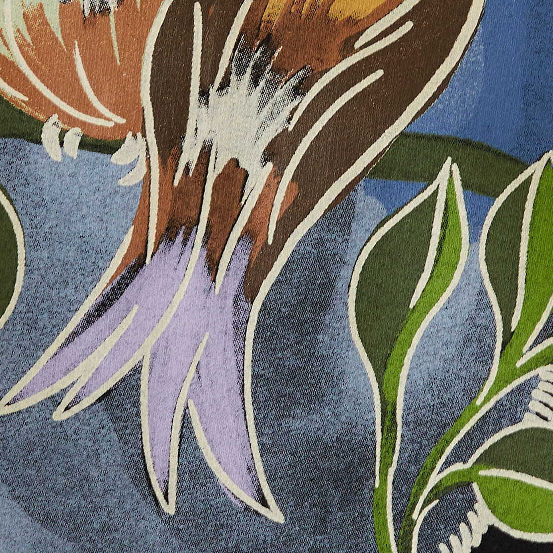 Detalle ampliado del estampado del vestido de sudadera mostrando los elementos gráficos de los pájaros y hojas.