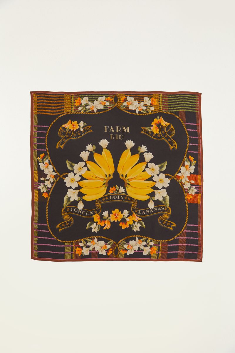 Pañuelo con diseño tropical de bananas y flores sobre fondo oscuro, mostrado en formato cuadrado.