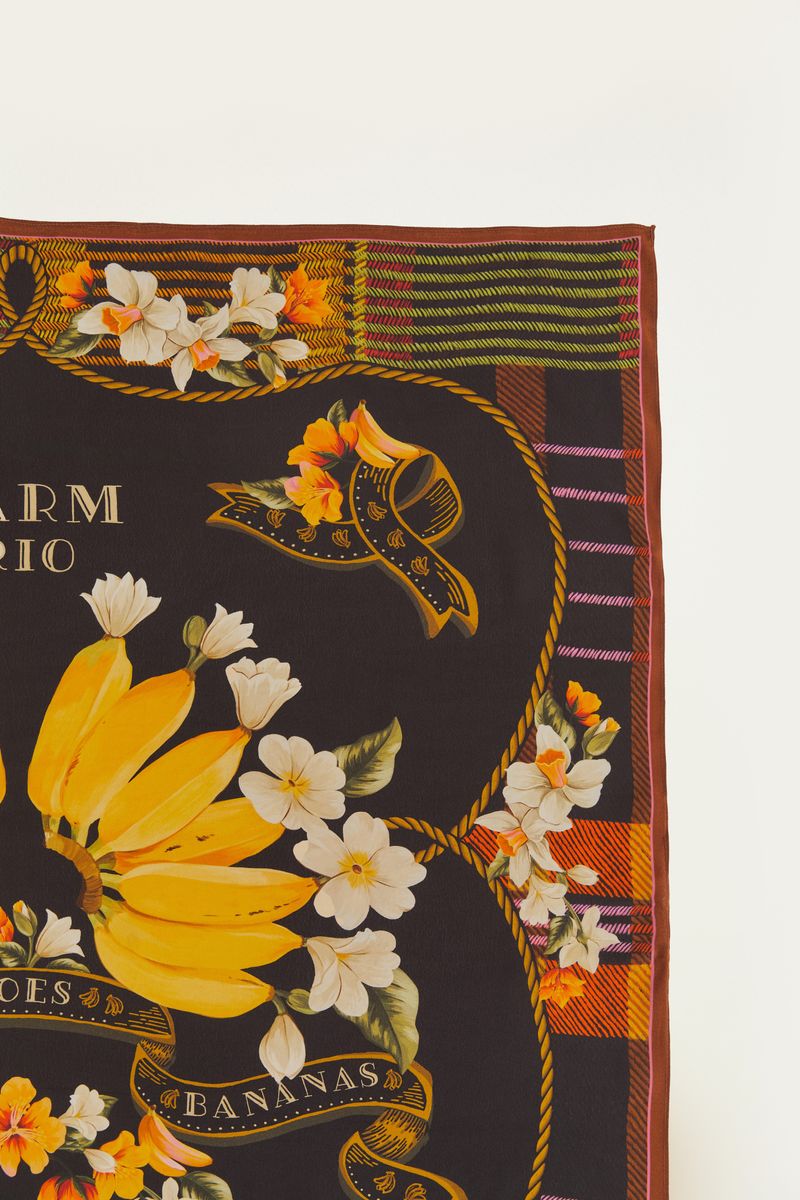 Detalle del diseño del pañuelo con bananas amarillas y flores blancas y naranjas.