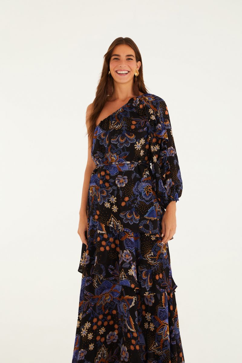 Vestido largo con estampado floral sobre fondo negro, modelo de un hombro, con mangas abullonadas y dobladillo en capas.