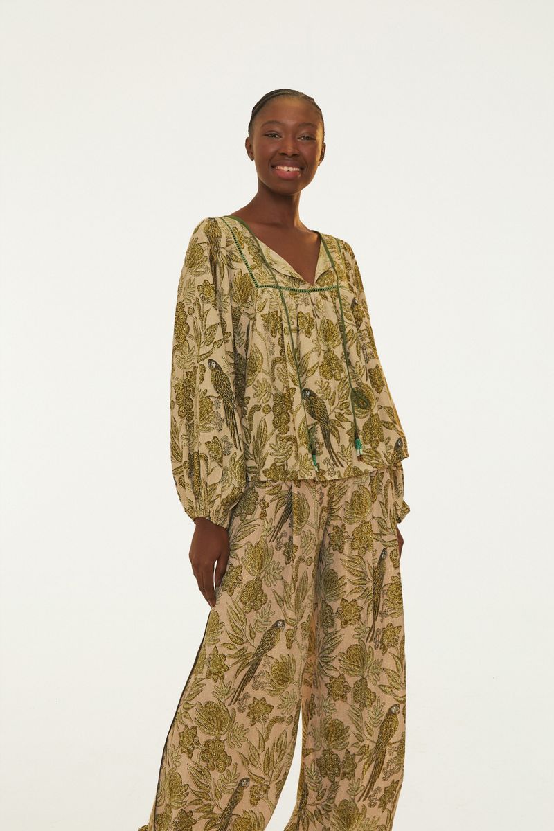 Vista lateral de un pantalón floral con estampado botánico en tonos verde claro y beige.
