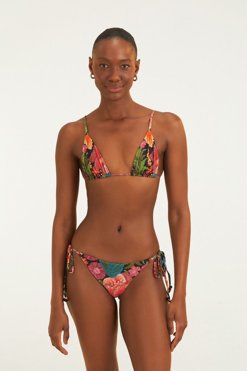 Modelo usando bikini con lacito bordadora con estampado floral tropical, vista lateral.