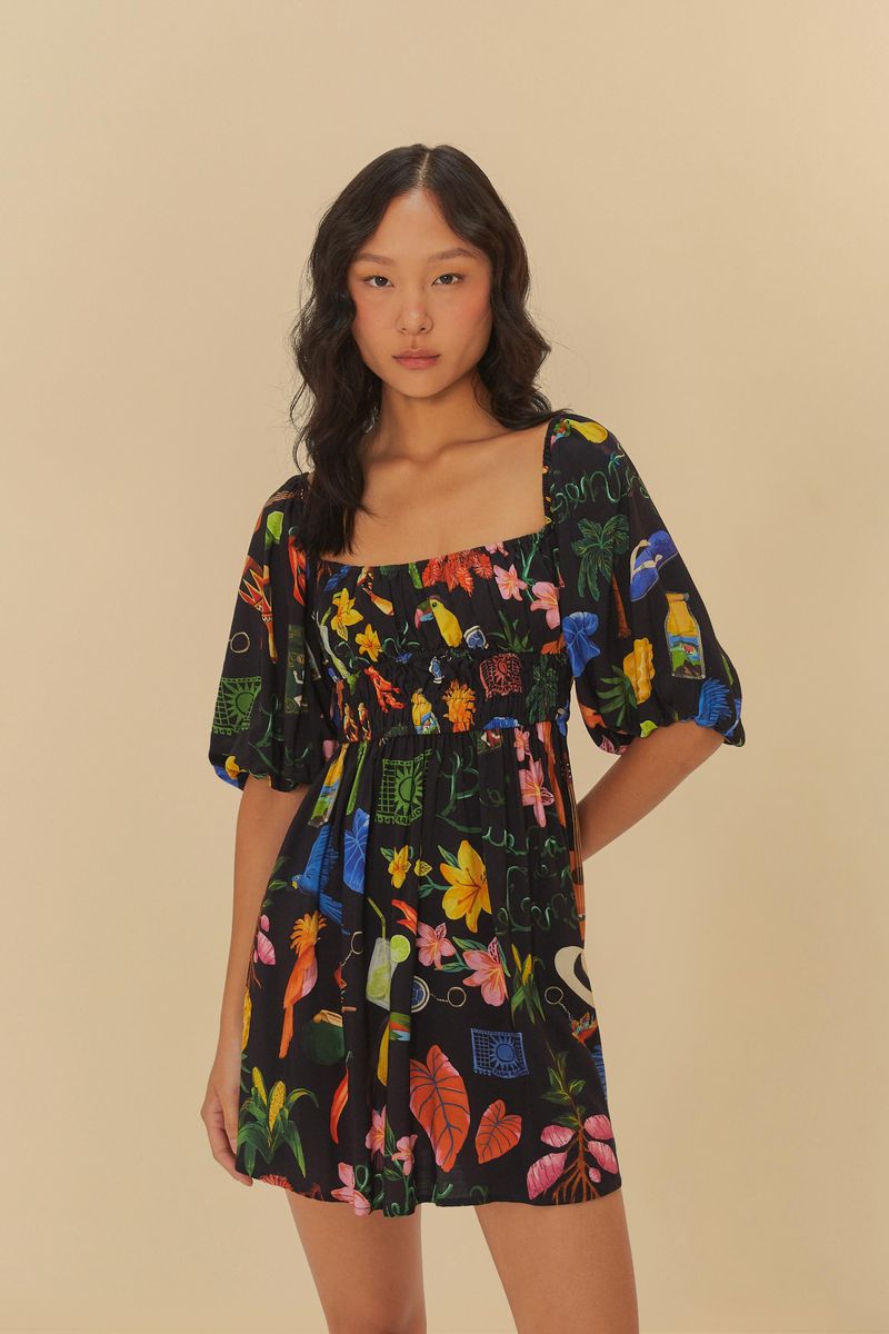 Imagen de un vestido corto estampado con fondo negro y elementos coloridos, exhibido en un modelo.