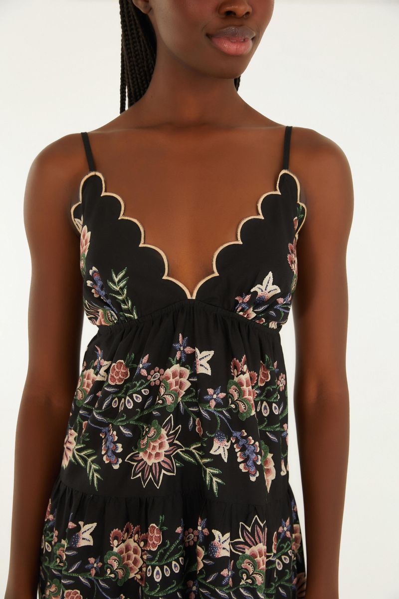 Detalle del corpiño del vestido con escote en forma de V y bordes ondulados.