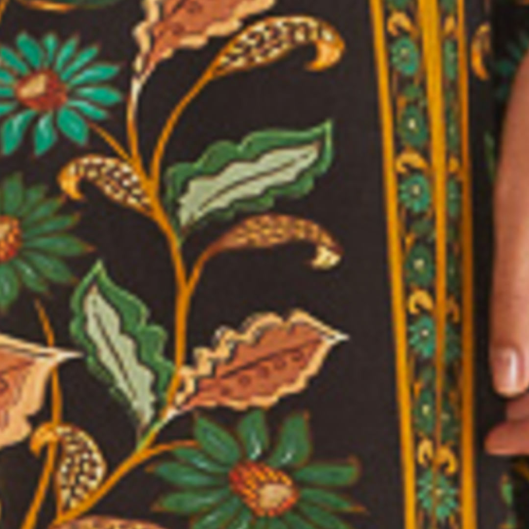 Imagen mostrando el estampado botánico de la Falda Godé Marcelle con detalles de flores y hojas en tonos vibrantes sobre fondo oscuro.