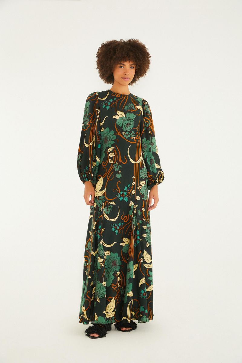 Vestido largo con estampado floral en fondo oscuro, mangas largas y caída fluida.