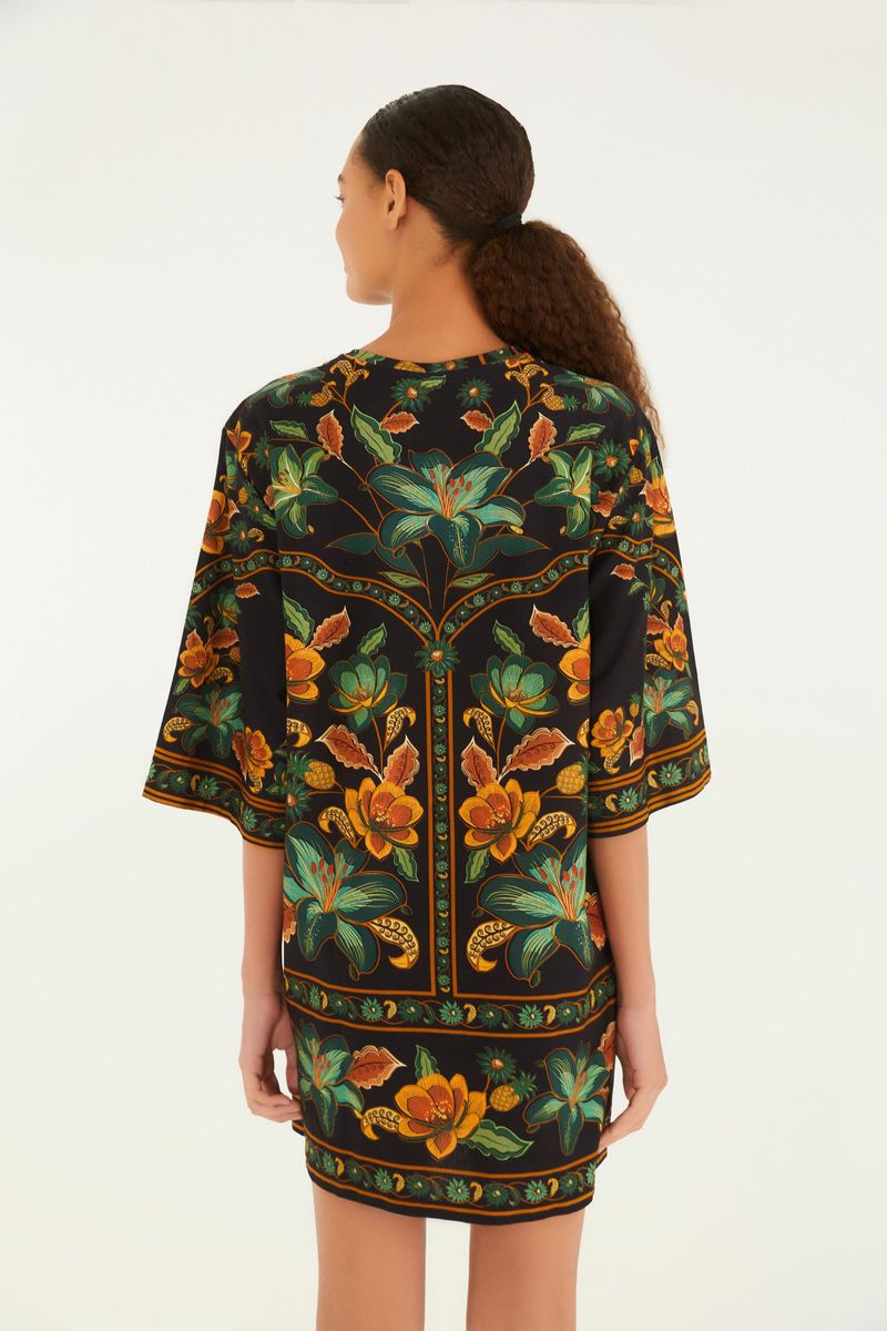 Vista trasera del vestido tipo camiseta con estampado floral vibrante sobre fondo negro.