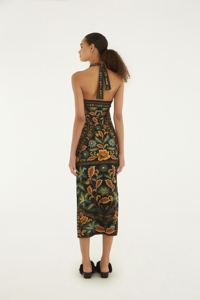 Vestido midi con estampado floral en fondo oscuro, tirantes cruzados y largo por debajo de la rodilla, visto de perfil.