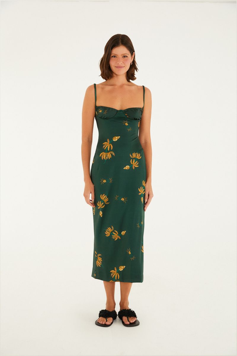 Modelo luciendo un vestido midi verde con estampado de bananas y follajes, tirantes delgados y escote estructurado, sobre fondo blanco.