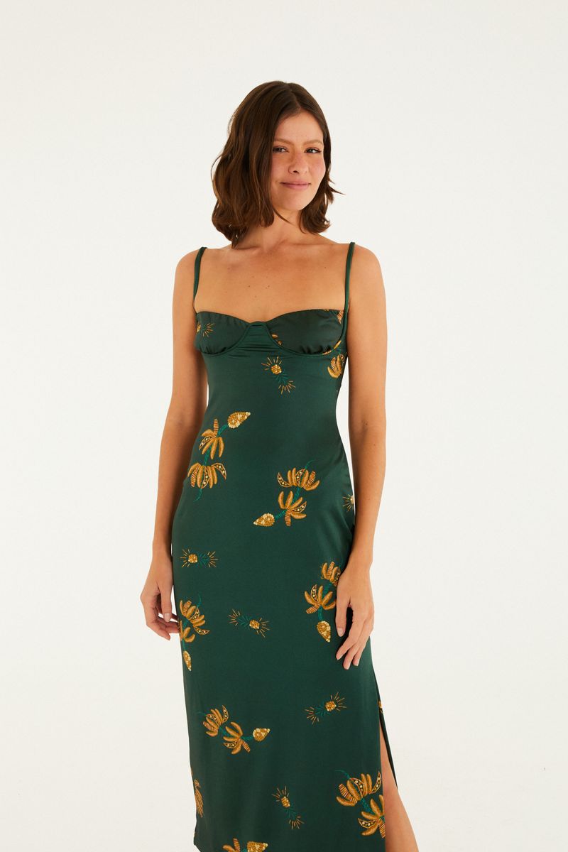 Close-up del vestido midi verde con estampado de bananas y follajes, destacando el escote estructurado y los tirantes delgados, sobre fondo blanco.