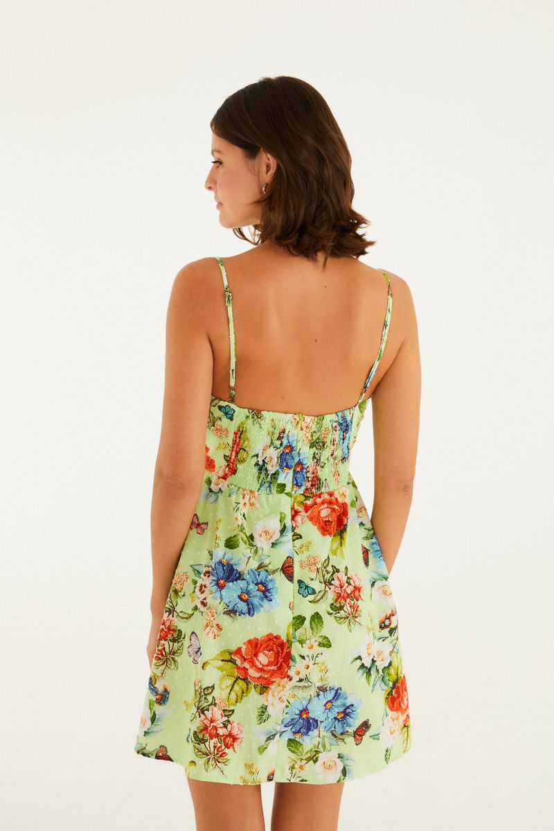 Vestido corto con estampado floral sobre fondo verde, tirantes delgados y escote en forma de corazón, visto desde atrás.