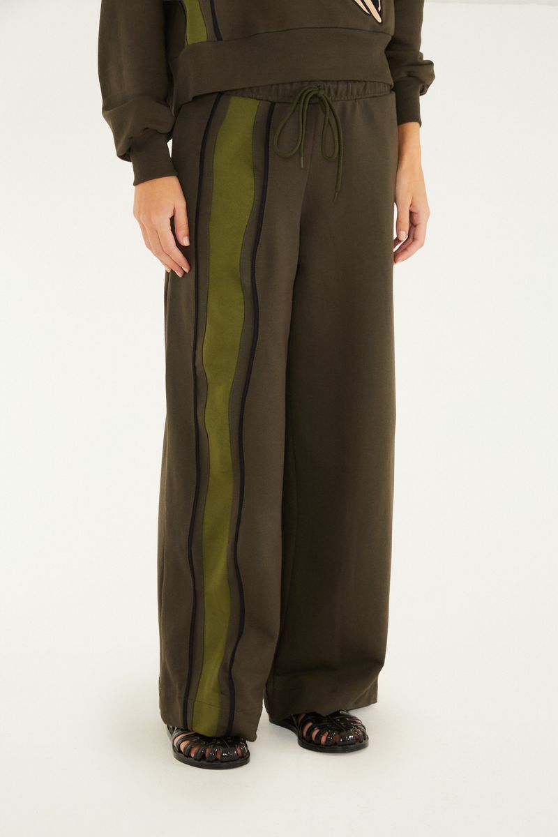 Imagen de un pantalón tipo pantalona verde oscuro con detalles geométricos en negro, mostrando el detalle de la cintura con amarre.