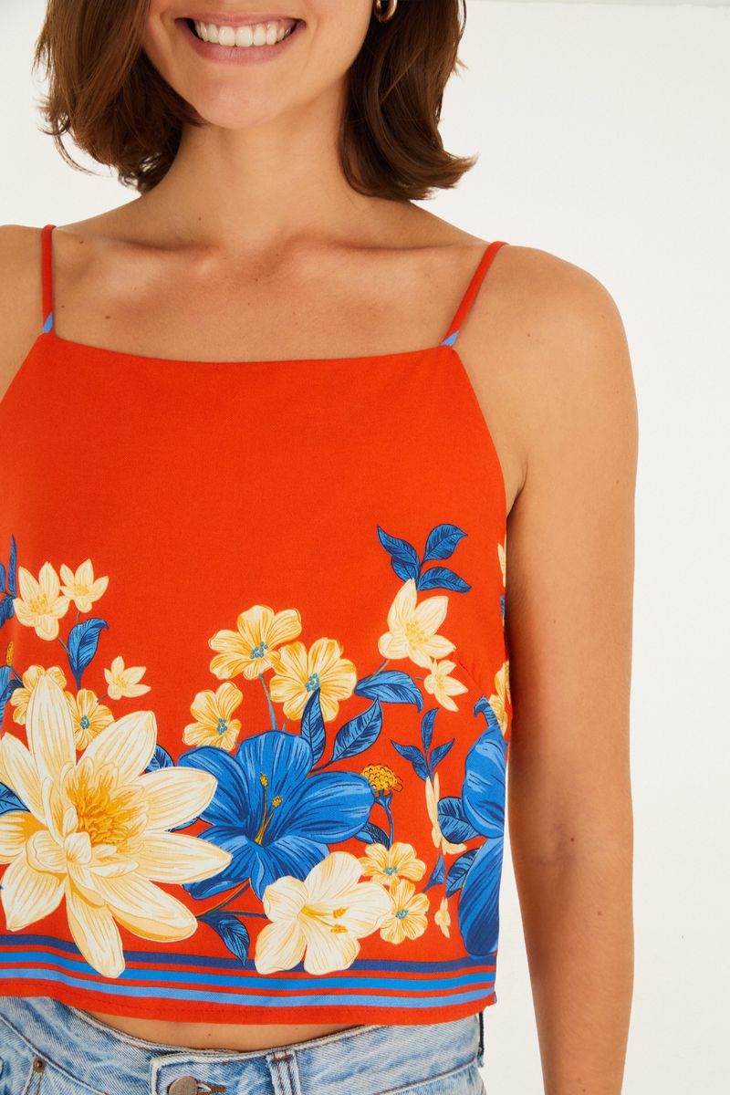 Detalle del estampado floral vibrante en fondo rojo de la camiseta.